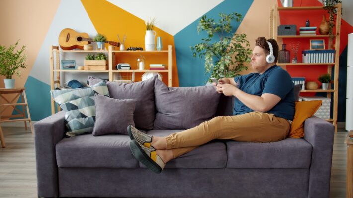 Man with headphones plays video game on couch