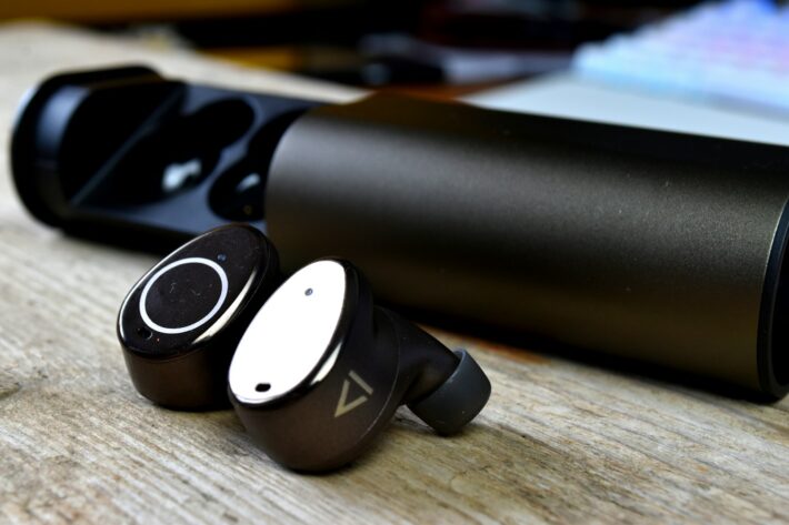 Wireless earbuds with charging case on wooden surface
